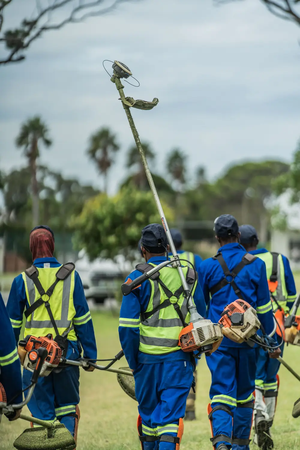 Lawnworx crew walking together with their brush cutters on a work site